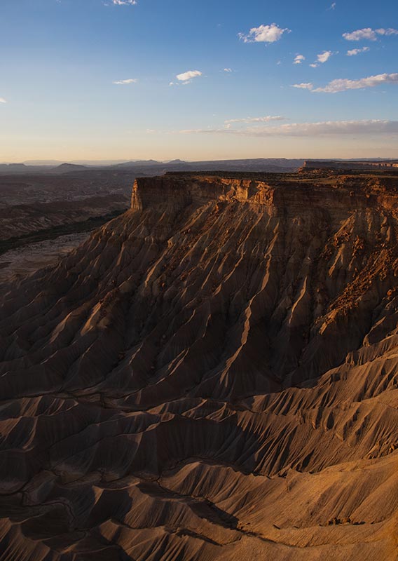 A desert cliffside rises from above a wide river valley.